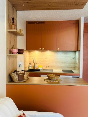 une cuisine avec des armoires en bois et des paniers sur un comptoir dans l'établissement Appartement 5 pers Serre Chevalier Cabane Bohème, à Saint-Chaffrey