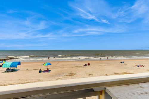 a beach with people and umbrellas and the ocean at A Shore Thing in Edisto Beach