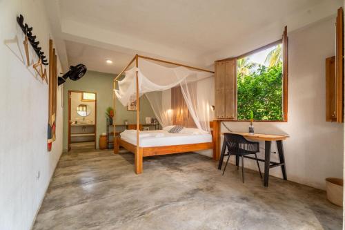 a bedroom with a bed and a desk and a window at Casa Chapolin Boutique Guesthouse in Palomino
