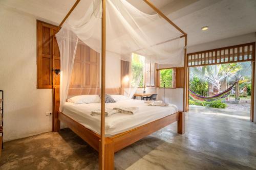 a bedroom with a canopy bed and a table at Casa Chapolin Boutique Guesthouse in Palomino