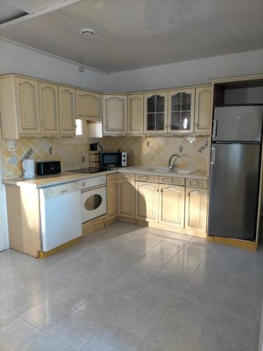 une cuisine avec des armoires en bois et un réfrigérateur en acier inoxydable dans l'établissement Appartement en bord de mer, à La Londe-les-Maures