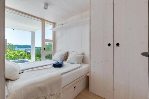 a white bedroom with a window and a bed at Villa Nautilus Buqez Resort in Drage