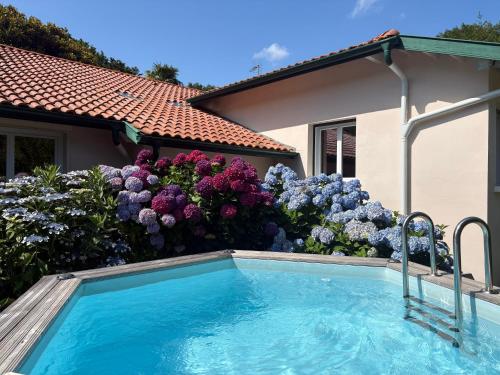 une piscine devant un jardin de fleurs dans l'établissement Villa de charme parc fleuri, arboré et piscine à BIARRITZ, à Biarritz
