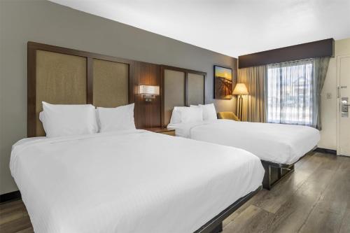 two beds in a hotel room with white sheets at Best Western Salisbury Plaza in Salisbury