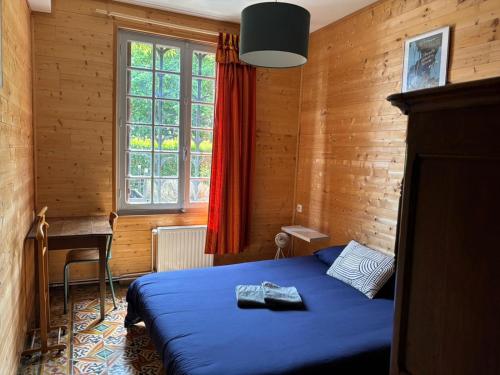 une chambre avec un lit bleu et une fenêtre dans l'établissement Béhuard : Maison vue Loire, à Behuard