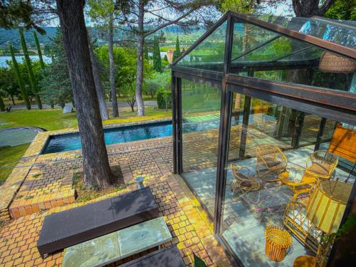 une maison de verre avec une piscine et un arbre dans l'établissement L'Atelier d'artiste, Lodge contemporain à ciel ouvert avec piscine, à Saint-Saturnin-lès-Apt