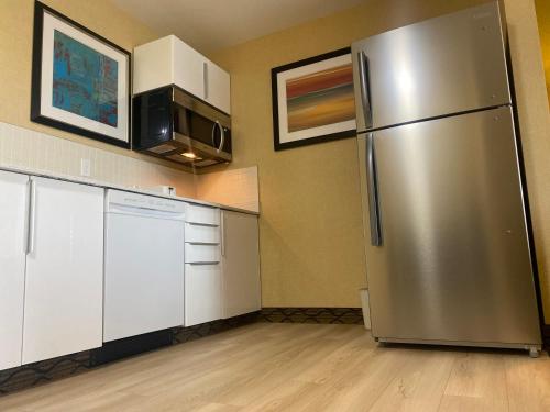 a kitchen with a stainless steel refrigerator and white cabinets at Wingate by Wyndham Fort Saskatchewan in Fort Saskatchewan