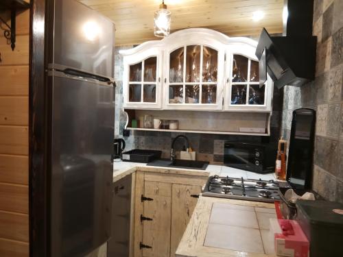 a kitchen with wooden cabinets and a stainless steel refrigerator at Pokoje Apartamenty w Dolinie Rospudy in Skazdub Stary