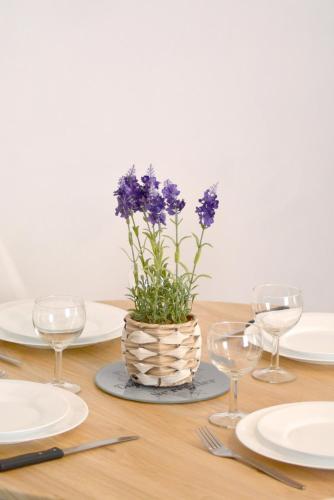 a table with plates and glasses and a vase with purple flowers at Le Bourgneuf in Chartres
