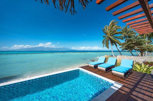 a pool on the beach with chairs and the ocean at Villa Tohora in Teavaro