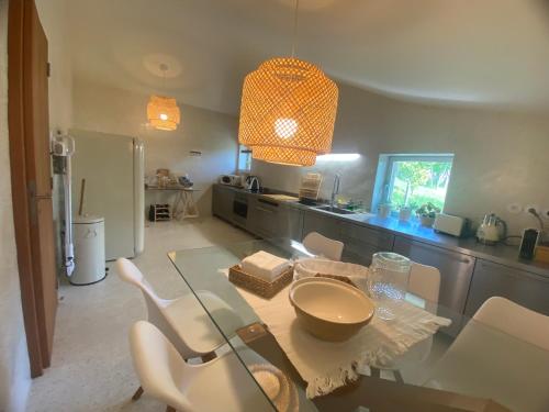 una cucina con tavolo in vetro e sedie bianche di Douro Wellspring a Santa Marinha do Zêzere