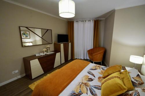 een slaapkamer met een bed, een bureau en een televisie bij Madalena Sunset by Mill Escapes in Madalena do Mar