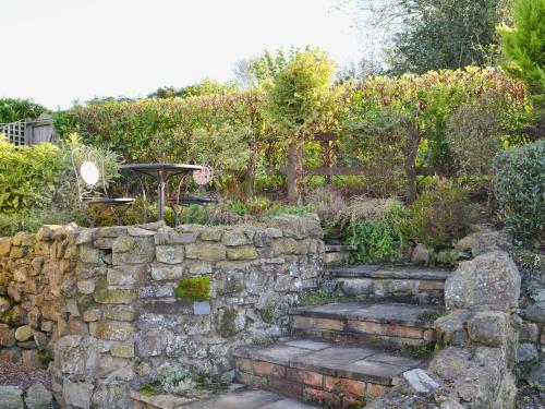 a garden with a stone wall and stairs at Angel Barn in Farden