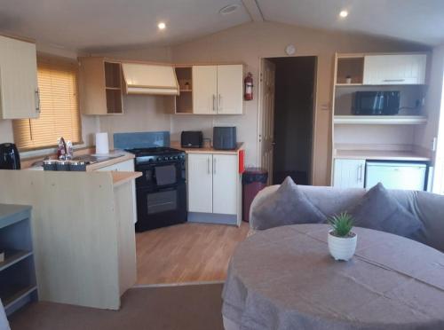 a kitchen and living room with a couch and a table at Happy Days Chapel st Leonard's The Ocean Pearle in Chapel Saint Leonards
