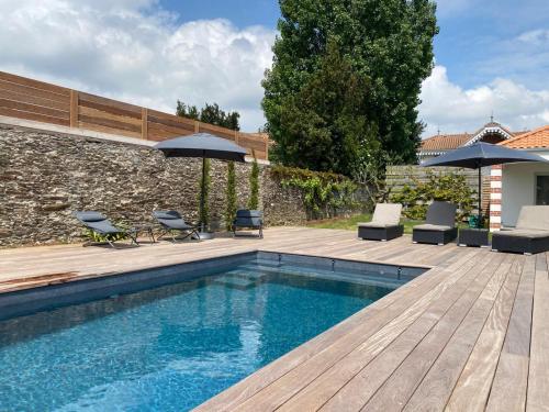 une piscine avec chaises et parasols à côté d'un bâtiment dans l'établissement Le Clos de Jade - Appt 3 étoiles avec piscine partagée, à Pornic