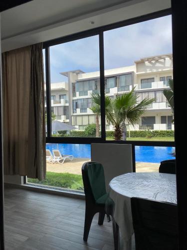 a room with a table and a view of a building at Appartement - Dar Bouazza spacieux avec piscine à Dar Bouazza in Dar Bouazza