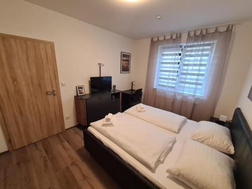 a bedroom with a bed with white sheets and a window at Exclusive HOTEL Lipno Wellness & SPA in Frymburk