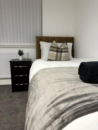 una camera da letto con un letto con un cuscino e un comodino di Spacious & Modern house in St Helens a Saint Helens