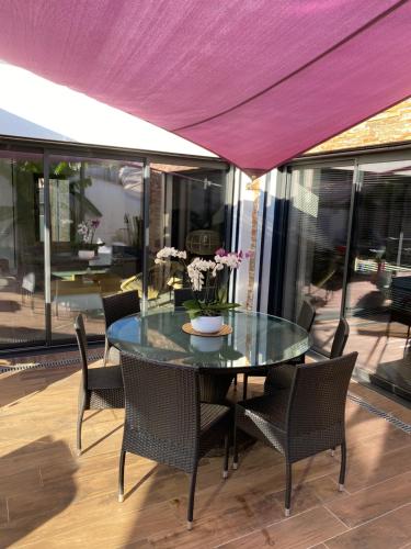 une table de salle à manger avec des chaises et un auvent violet dans l'établissement Kilono, à La Garde