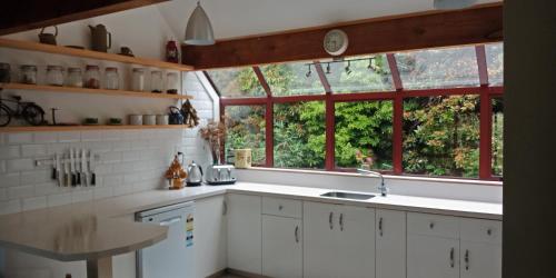 a kitchen with white cabinets and a large window at Okuti Retreat in Little River