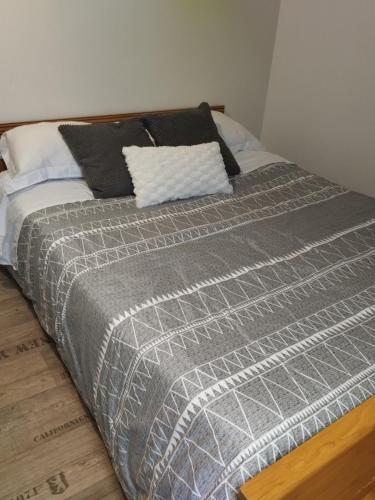 un lit avec une couverture grise et des oreillers noirs dans l'établissement Maison de ville à 10 min du PAL, à Dompierre-sur-Besbre