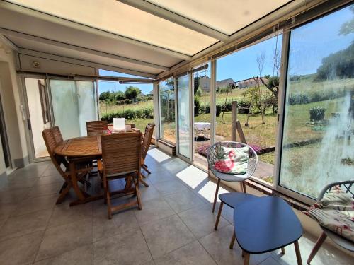 - une salle à manger avec une table, des chaises et de grandes fenêtres dans l'établissement Les 3 champs, à Lavault-Sainte-Anne