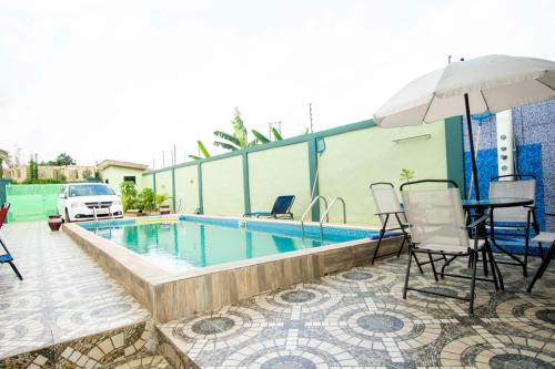 a pool with a table and chairs and an umbrella at Luxurious Akwaaba Villa in Kwesimintim