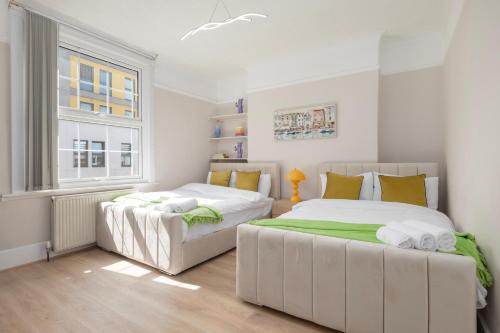 two beds in a bedroom with a window at Camden Town Apartments in London