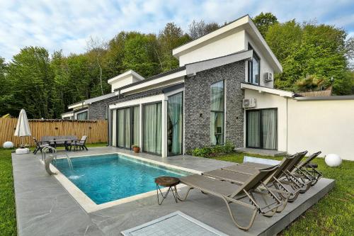 una piscina con sillas y una casa en New Balturk Nature Villas, en Sapanca