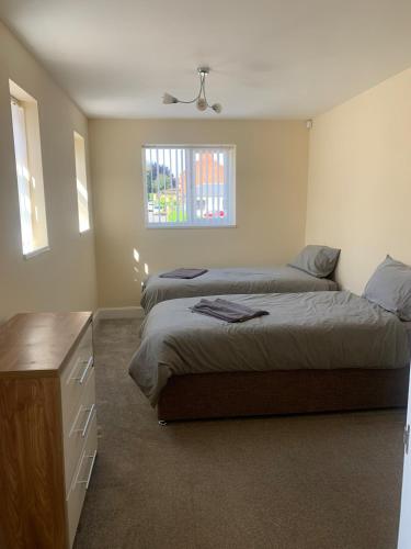 a bedroom with two beds and a dresser and a window at Large 3 Bed contractor House sleeps 7 in Retford