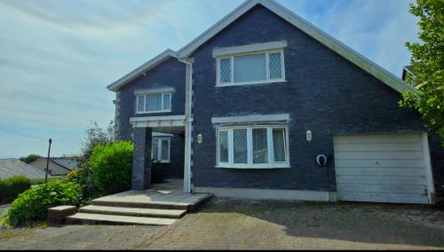 a blue brick house with a garage at Luxury Seaview Escape - Mumbles in Oystermouth
