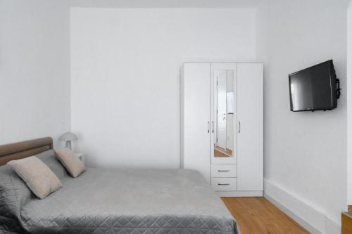 a white bedroom with a bed and a tv at Harmony Point in Bar