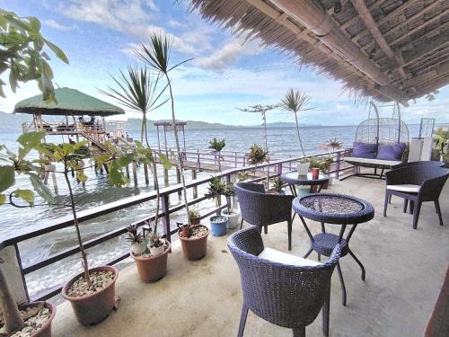 a patio with tables and chairs and the ocean at CHUE&LARRY'S BEACHSIDE HOMESTAY in Libagon