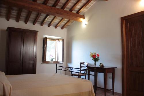 Schlafzimmer mit einem Bett, einem Schreibtisch und einem Fenster in der Unterkunft Il Vallone di Melezzole in Melezzole