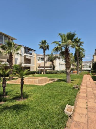 un parco con palme di fronte a un edificio di Résidence balnéaire Les perles de Tamaris a Tamaris