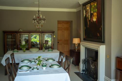 a dining room with a white table and a fireplace at Outwood House in Horsforth