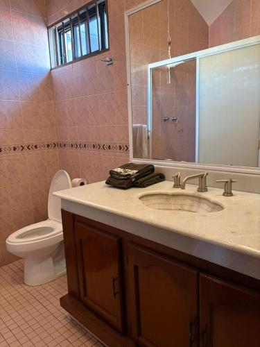 a bathroom with a sink and a toilet and a mirror at Domus Áurea in Mazatlán