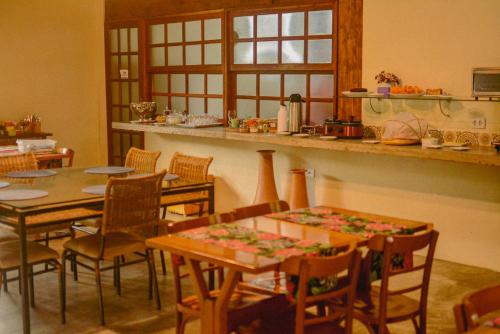 a dining room with tables and chairs and a kitchen at Pousada Zazen in Vale do Capao