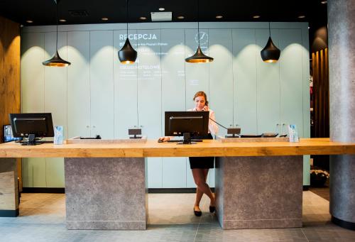 a woman standing behind a large desk in a lobby at Ibis Poznan Polnoc in Suchy Las