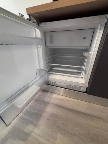 un réfrigérateur vide avec sa porte ouverte et ses étagères vides dans l'établissement Studio rénové - Centre Ville de semur, à Semur-en-Auxois