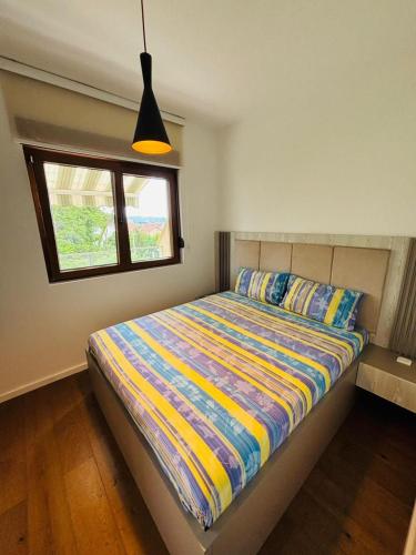 a bedroom with a bed with a colorful comforter and a window at Lazure apartment in Tivat