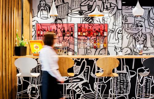 a person walking past a bar with a wall covered in graffiti at Ibis Poznan Polnoc in Suchy Las
