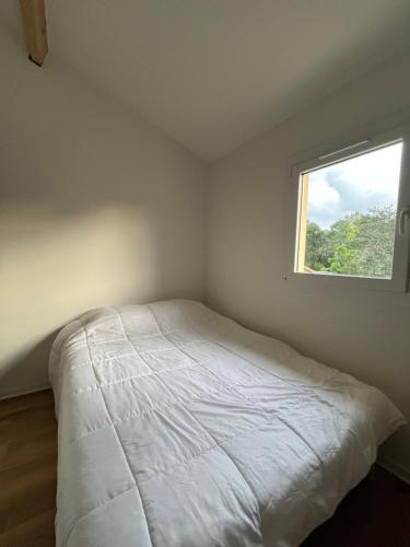 une chambre avec un lit blanc avec une fenêtre dans l'établissement Maison zen Lacanau Océan 3 personnes, à Lacanau