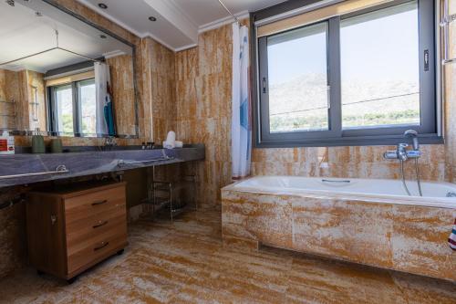 a bathroom with a tub and a large window at Villa Memories in Kineta