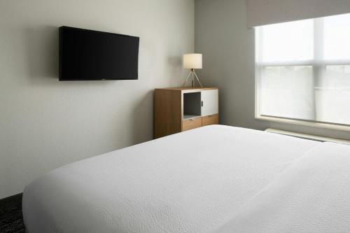 a bedroom with a white bed and a flat screen tv at TownePlace Suites by Marriott Lafayette in Lafayette
