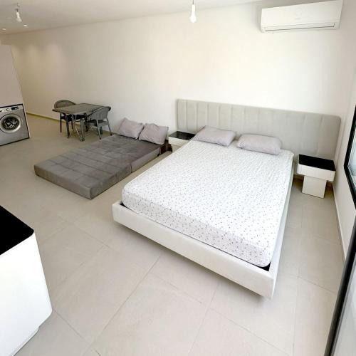 a white bedroom with a bed and a table at Holidays in Sousse Monastir 31 in Monastir