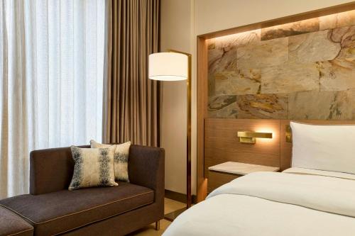 a hotel room with a bed and a chair at The Westin Flushing LaGuardia Airport in Flushing
