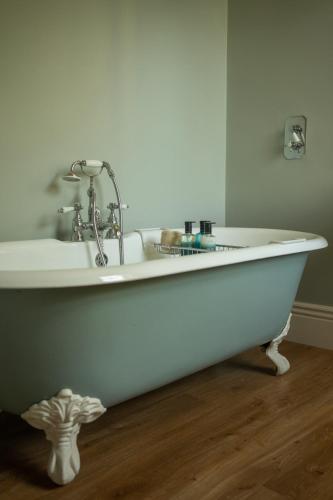 a white bath tub with a sink in a room at Outwood House in Horsforth