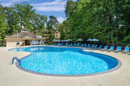 a large swimming pool with blue chairs and trees at Marriott's Manor Club at Ford's Colony in Williamsburg
