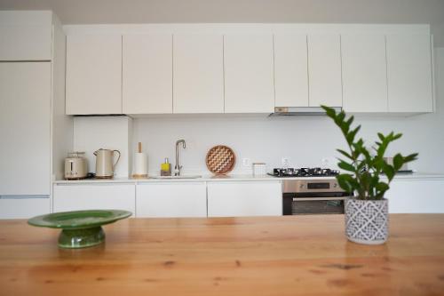 a kitchen with white cabinets and a wooden table with a plant at Sky House by Everkind in Viana do Castelo